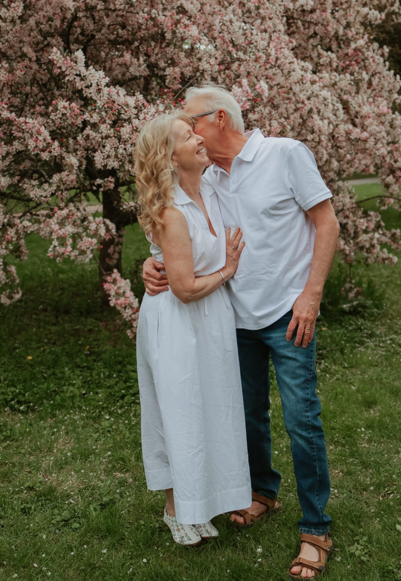 Couple embracing among blossoming garden flowers in natural light